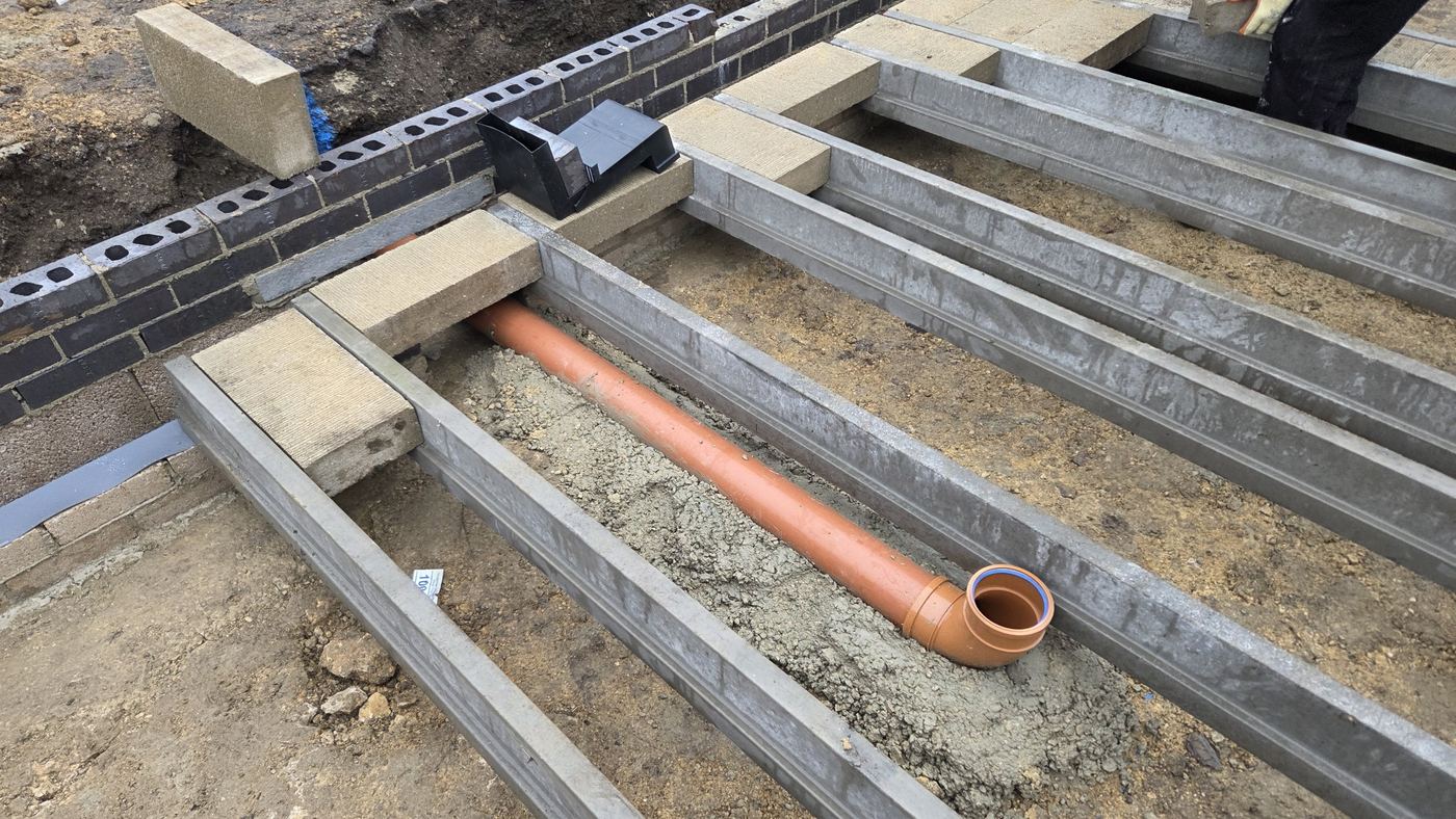 Beam and block floor. Floor beams set over the new drainage and brick plinth.