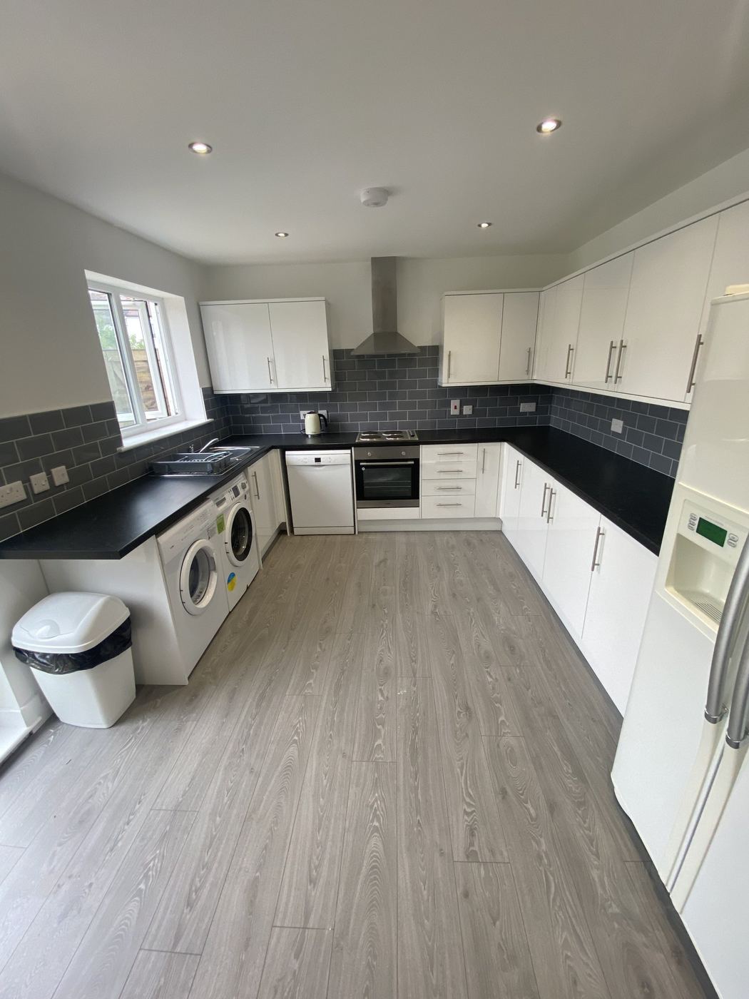 White gloss U-shaped kitchen with grey metro tiles